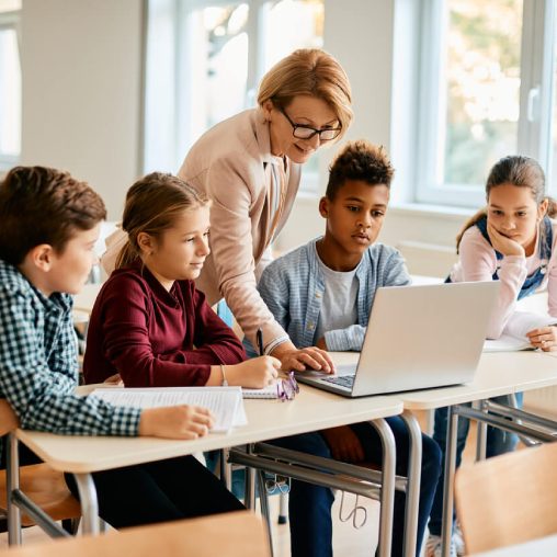 Teacher and children in a classroom looking at a tablet device